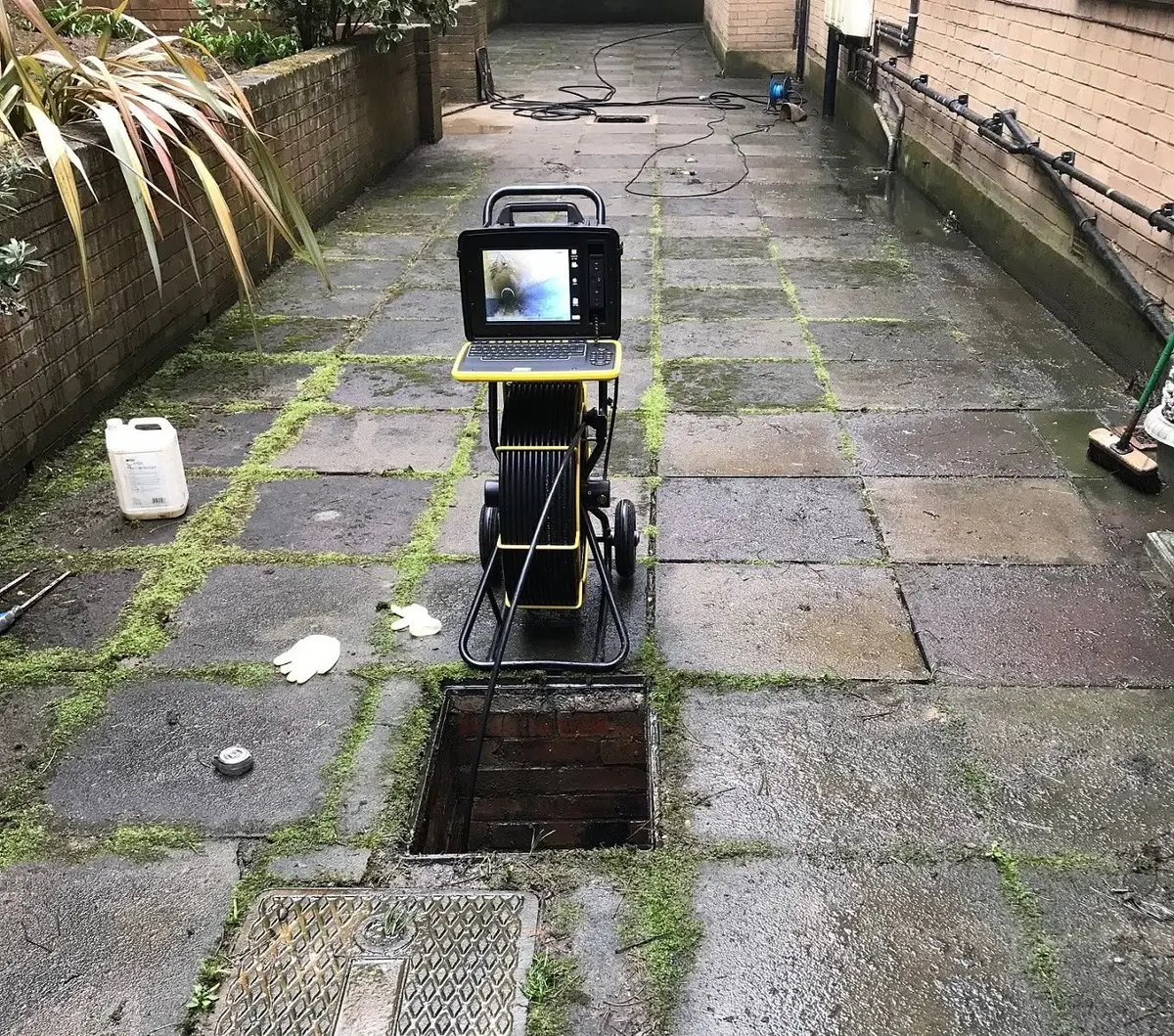 CCTV drain survey camera set up beside an open inspection chamber